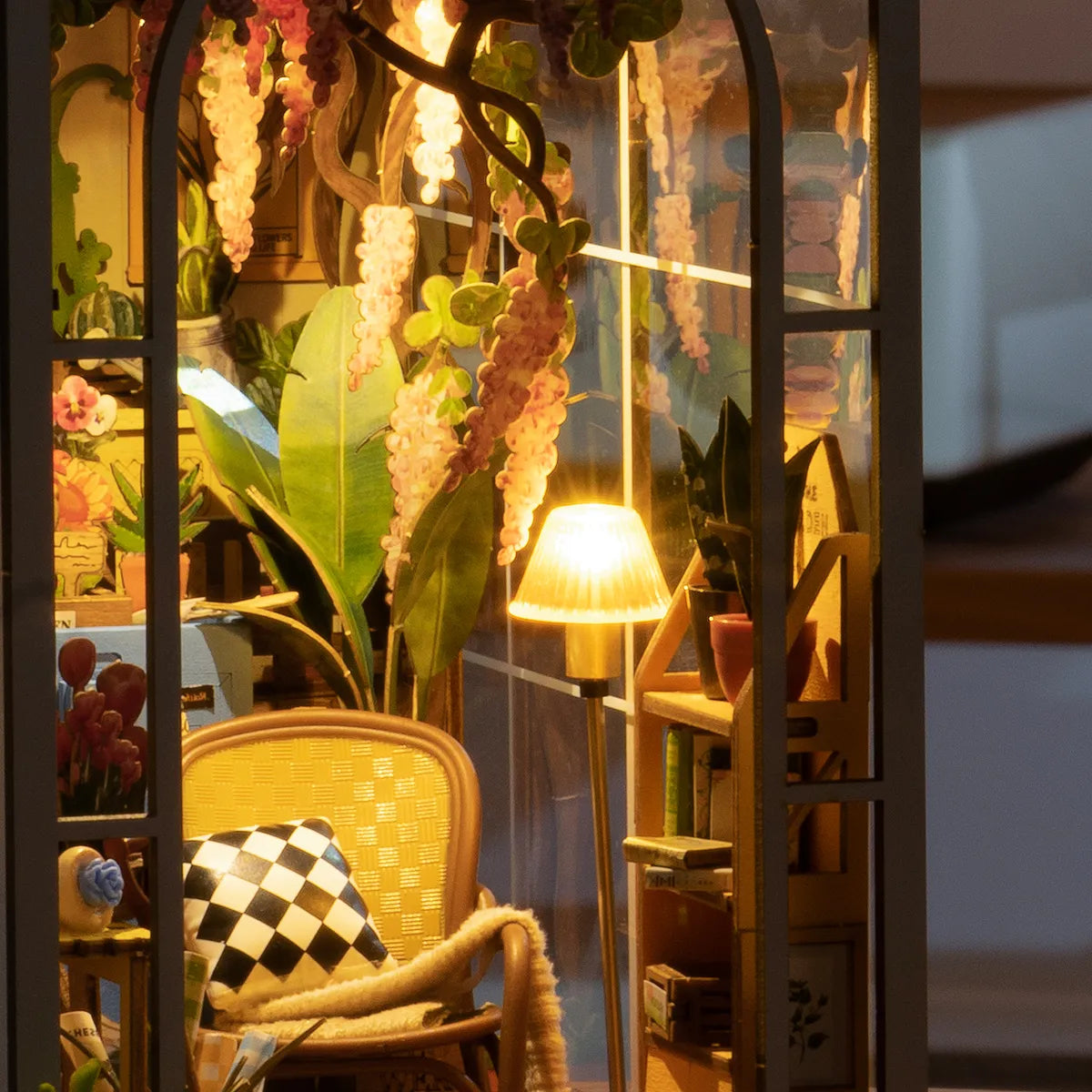 Detalle del sillón, la lámpara encendida y las plantas de Garden House.