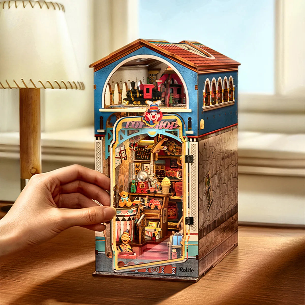 Una mano junto al frontal de Treasure Toy Shop montado sobre una mesa.