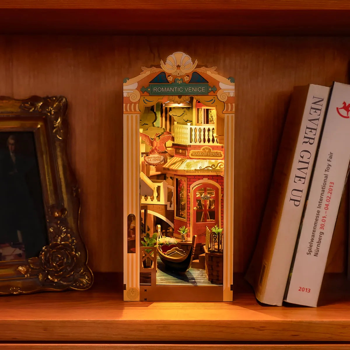 Romantic Venice iluminado junto a libros en una estantería de madera.