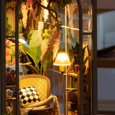Detalle del sillón, la lámpara encendida y las plantas de Garden House.