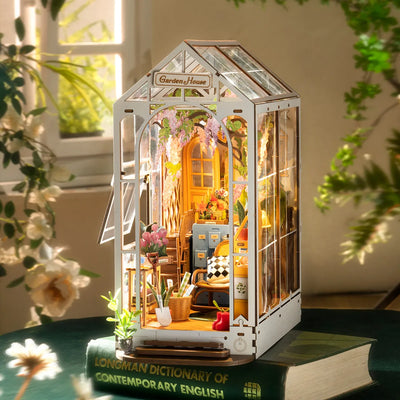 Garden House iluminado sobre un libro junto a una ventana y flores.