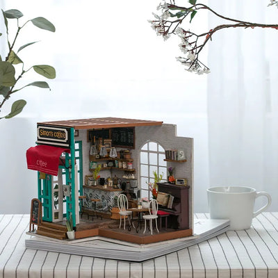 Simon’s Coffee sobre libros apilados junto a una taza y plantas.