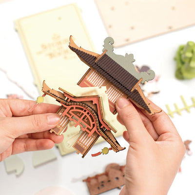Manos ensamblando el tejado de una construcción de Falling Sakura.