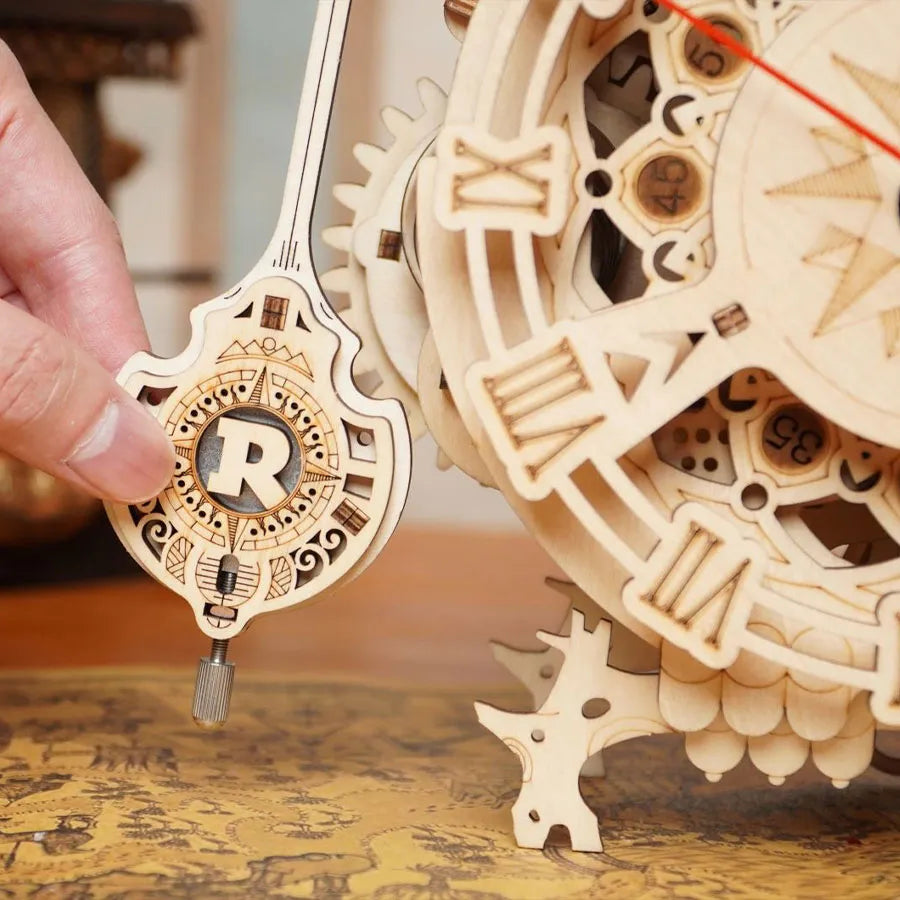 Una mano sostiene el péndulo de madera de Owl Clock.