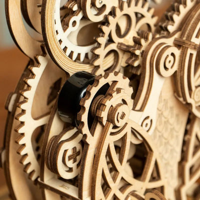 Detalle de los engranajes de madera y un mando negro de Owl Clock.