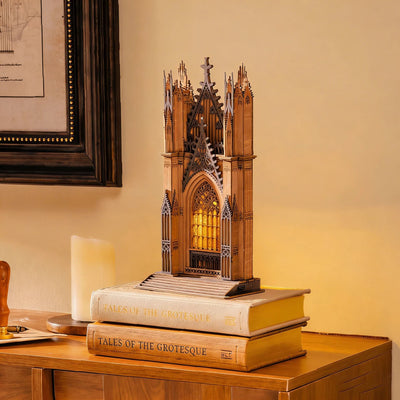 Twin-Tower Cathedral iluminada sobre libros apilados junto a una vela.