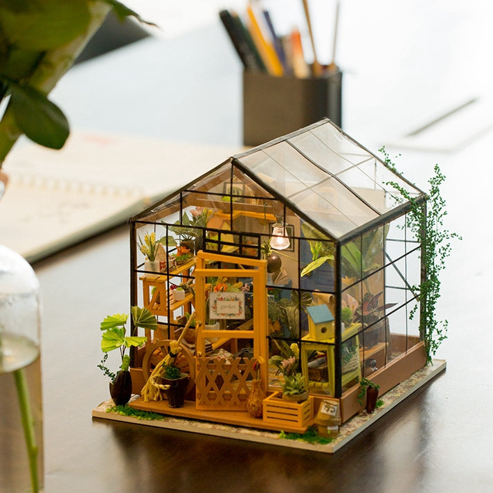 
Cathy’s Flower House sobre una mesa, junto a una planta y un recipiente con lápices