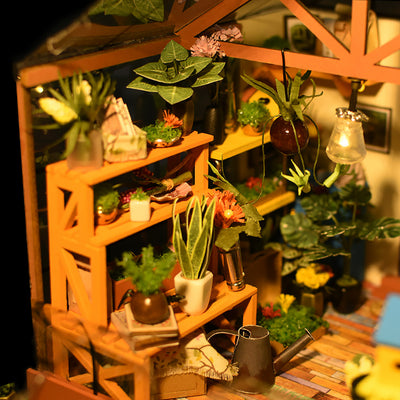 Detalle del interior de Cathy’s Flower House con estanterías, macetas y plantas iluminadas