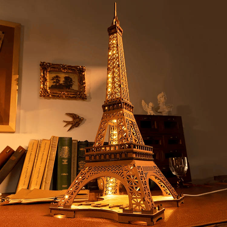 
Torre Eiffel iluminada junto a libros en una habitación cálida · Rolife
