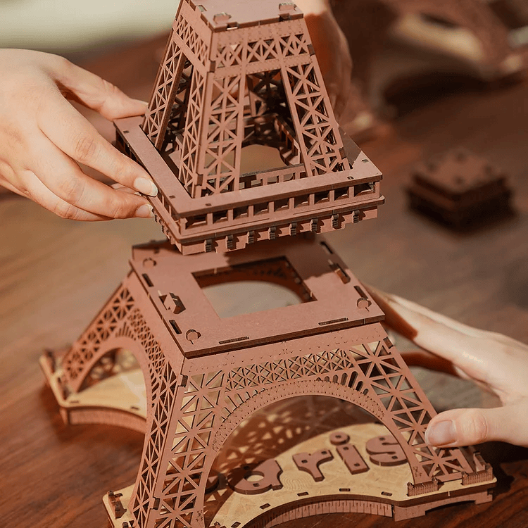 
Manos encajando una sección de la Torre Eiffel · Rolife