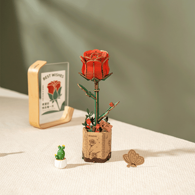 Rosa roja de madera en su soporte junto a pequeños objetos de escritorio · Rowood