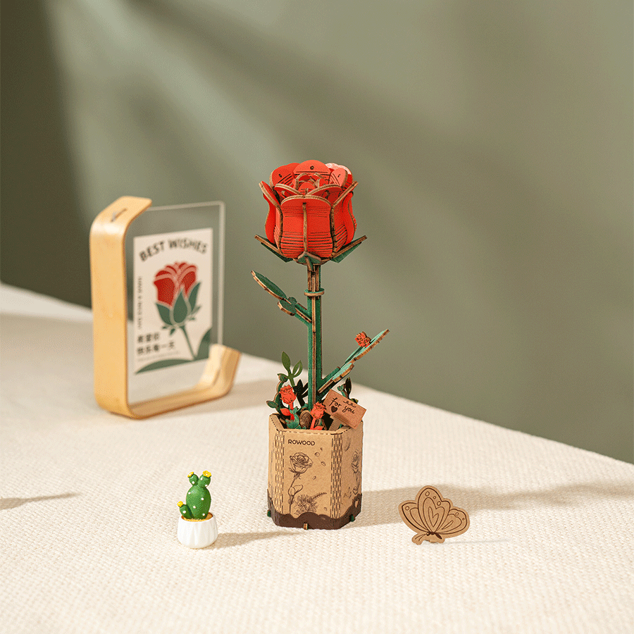 
Rosa roja de madera en su soporte junto a pequeños objetos de escritorio · Rowood