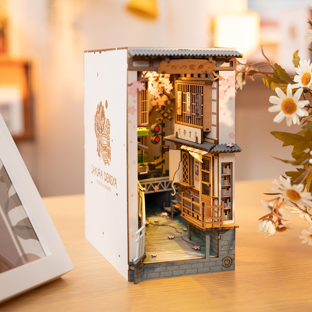 Vista en tres cuartos de Sakura Densya , con panel lateral blanco, tejados y edificios japoneses en miniatura.