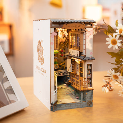 Vista en tres cuartos de Sakura Densya , con panel lateral blanco, tejados y edificios japoneses en miniatura.