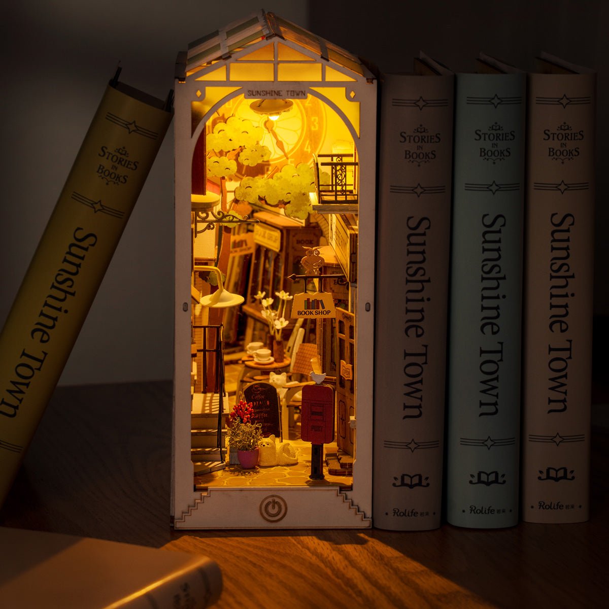 
Sunshine Town iluminado en un ambiente oscuro, con la calle en miniatura entre libros.
